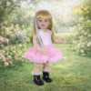 Enchanting Rainbow Dreams 22-inch reborn toddler standing in a garden wearing a sequined pink tutu dress and black boots with rainbow hair highlights