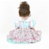 Back view Happy Birthday Girl reborn toddler doll showing brown curly hair and pastel cupcake print dress