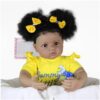 Sweet Sunshine Daisy reborn doll sitting with soft cloth body wearing yellow top and blue floral skirt