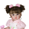 Clara Bloom reborn doll close-up showing curly brunette pigtails with pink bows and detailed facial features