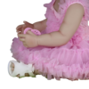 Detailed view of reborn doll hands holding pacifier wearing pink dress and white shoes