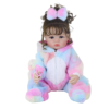Realistic reborn baby doll in rainbow unicorn onesie with hood and pacifier, full body sitting pose