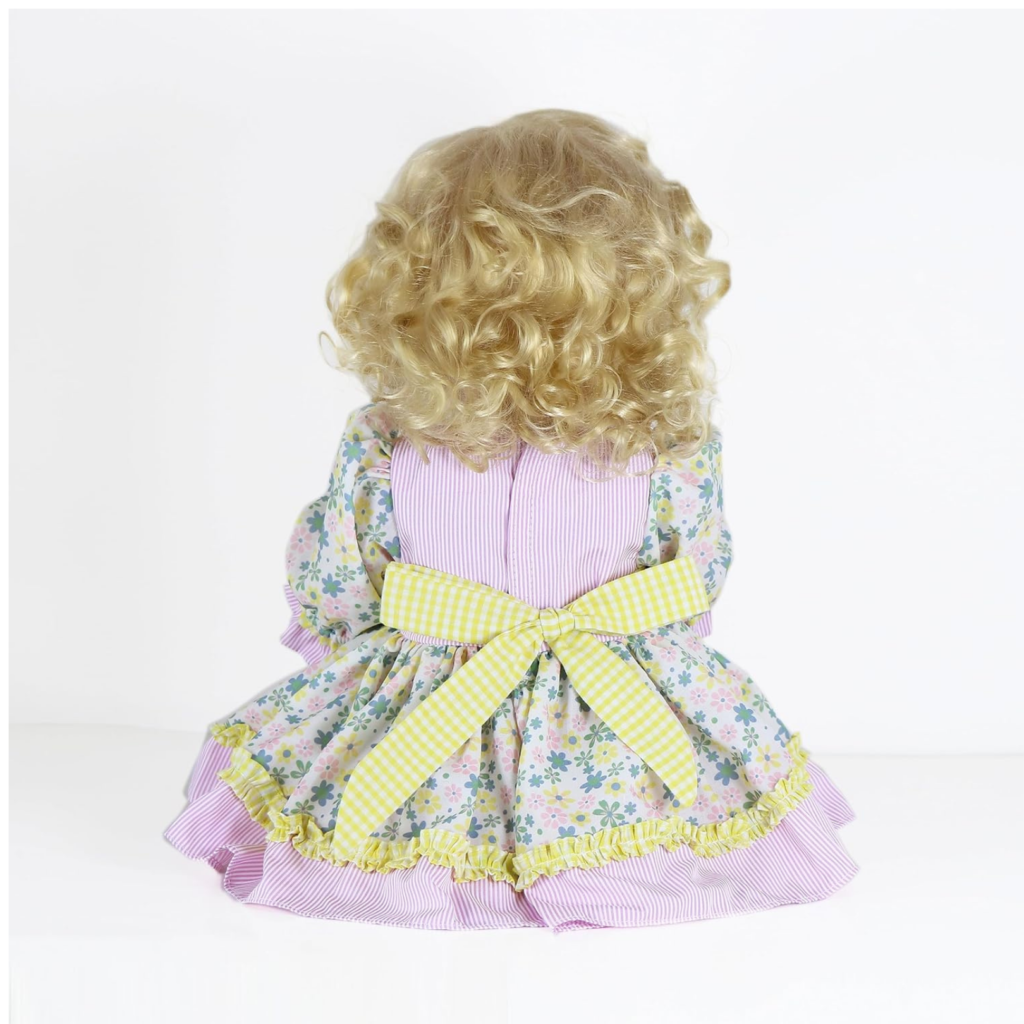 Sunny Flamingo Girl reborn doll back view showing curly blonde hair floral dress with yellow bow and detailed outfit design