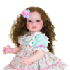 Sweet Curly Sunshine reborn toddler doll standing with curly hair pastel bow and colorful dress holding pacifier