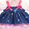 Close up galaxy print doll dress with stars planets pink trim and layered gingham ruffle