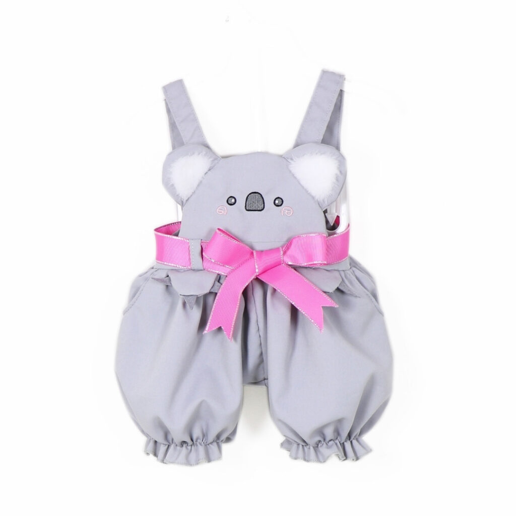 Close up of koala face design on doll outfit with plush ears and pink bow detail