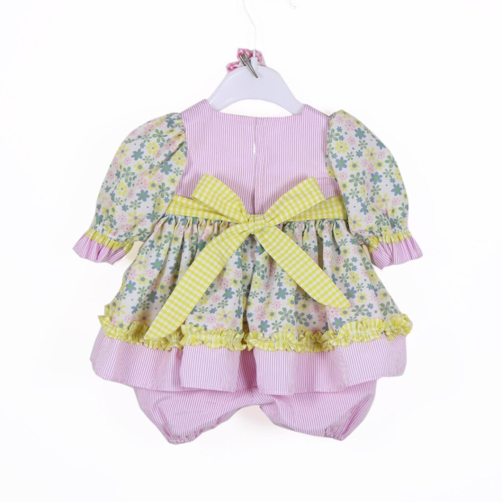 Back view of pastel floral ruffle doll dress with large yellow gingham bow and bloomers