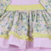 Close up of pastel floral print doll dress fabric with yellow gingham ruffle trim